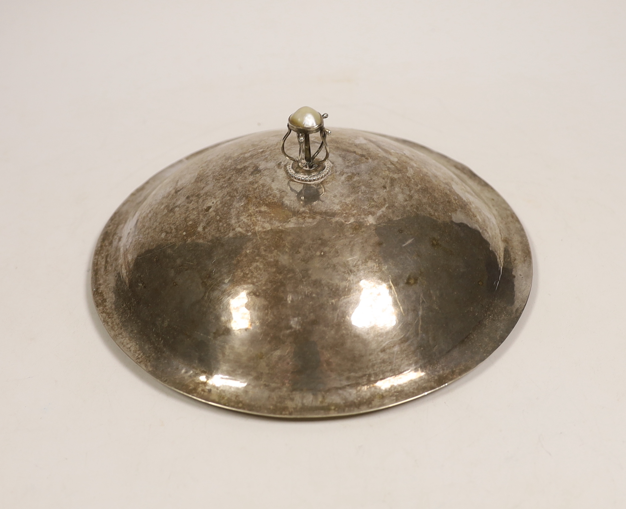 A Charles Robert Ashbee, Guild of Handicraft late Victorian hammered silver muffin dish cover, with a wire work finial set with a mother of pearl cabochon, London, 1899, diameter 20.3cm, gross 9.2oz.